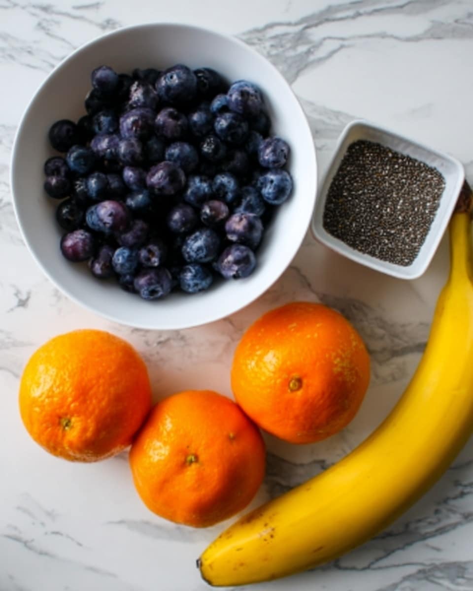 The image shows a white bowl full of dark blue or purple blueberries on the right side. Below the bowl is a small white container with black and white chia seeds. To the left of the bowl are three bright orange tangerines placed close together. Below the tangerines is a whole yellow banana. All items are on a white marbled surface. photo taken with an iphone --ar 4:5 --v 7