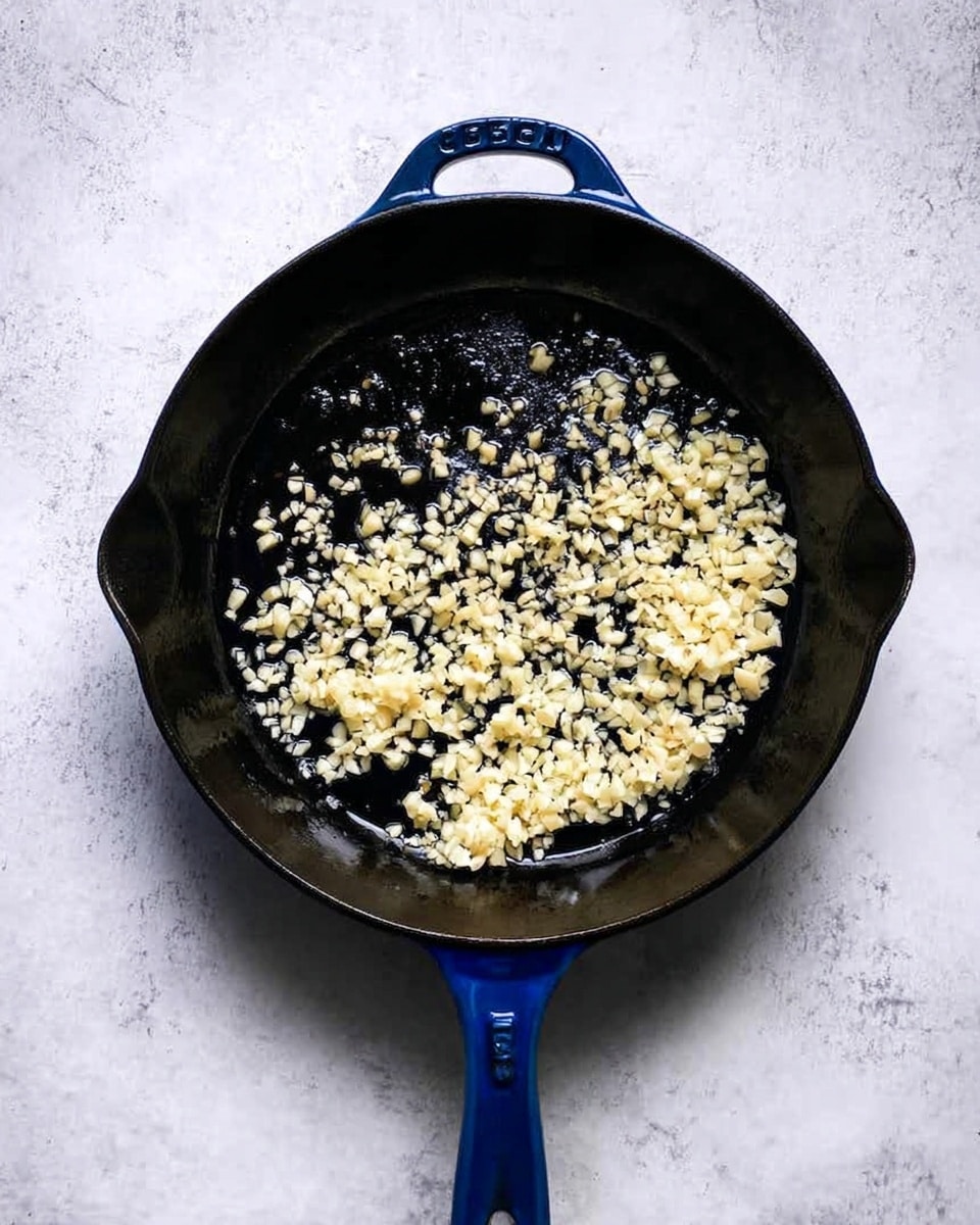 A black cast iron pan sits on a white marbled surface, holding two pieces of food being fried in hot oil. The pieces are golden brown with a rough, crispy texture, showing small browned spots and bubbles from frying. Light foam and oil surround the pieces in a circular motion in the pan. The pan handle points left, and the light gray surface contrasts with the dark pan and warm colors of the fried food. photo taken with an iphone --ar 4:5 --v 7