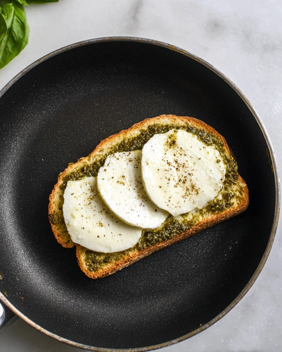 A tall stack of three grilled cheese sandwiches shows each sandwich made of two thick slices of golden brown toasted bread. Between the bread layers are thick, melted white cheese that stretches and drips down the sides, mixed with green pesto sauce and small bits of sun-dried tomatoes. The toasted bread has a crunchy texture with darker grilled marks, and the sandwiches are stacked unevenly on a dark surface with scattered pine nuts and green basil leaves around. The background is a soft white marbled texture. Photo taken with an iphone --ar 4:5 --v 7