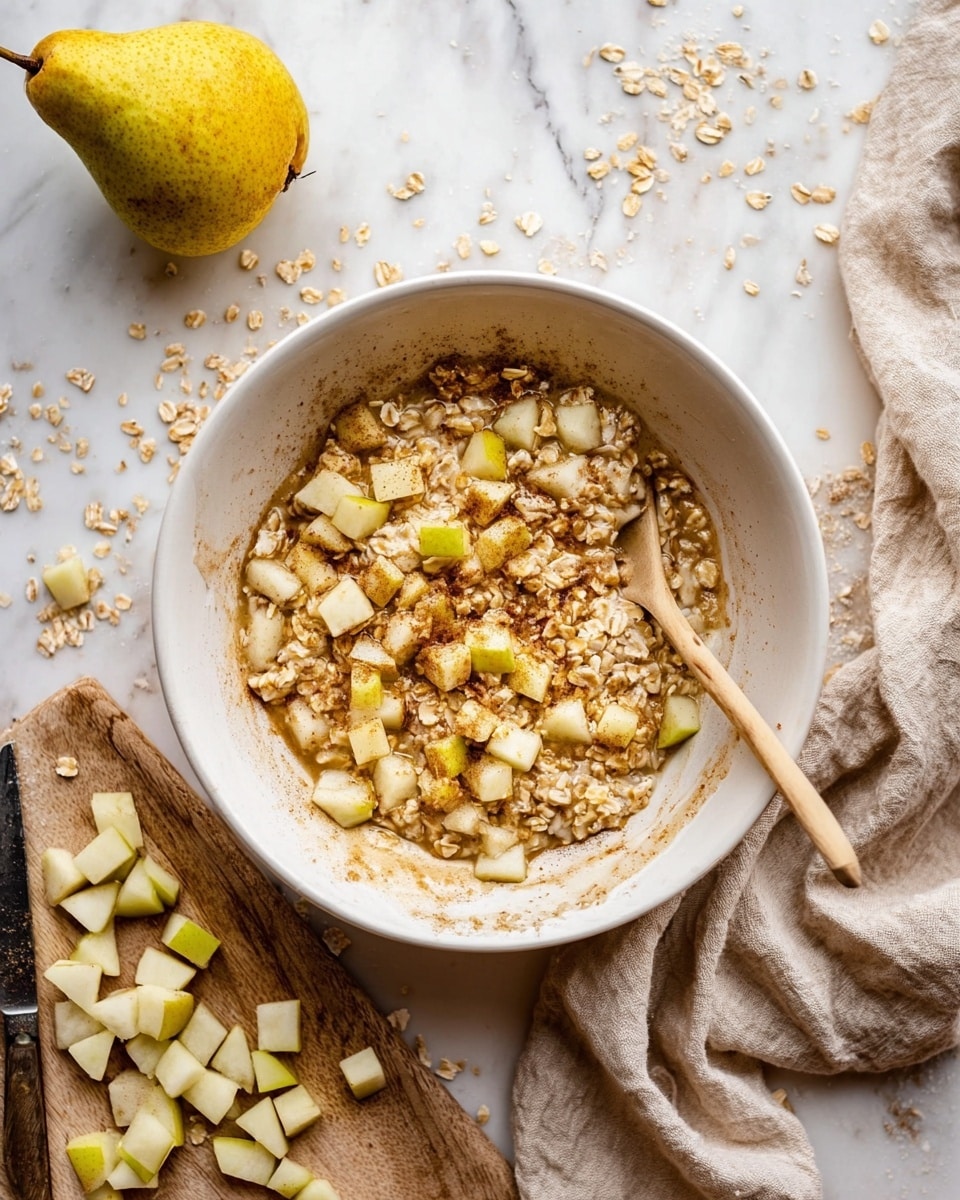 A white bowl filled with oatmeal and small light yellow and green cubes of pear mixed in, the oatmeal has a slightly soaked texture with some liquid around the edges and a brownish sprinkle, likely cinnamon, on top. A wooden spoon with a light handle rests inside the bowl on the right side. The bowl sits on a white marbled surface scattered with oat flakes, with a whole yellow and green pear at the top left. To the bottom left is a wooden board with more cubed pear pieces and a knife with a wooden handle. A beige cloth is loosely placed on the right side of the bowl. photo taken with an iphone --ar 4:5 --v 7