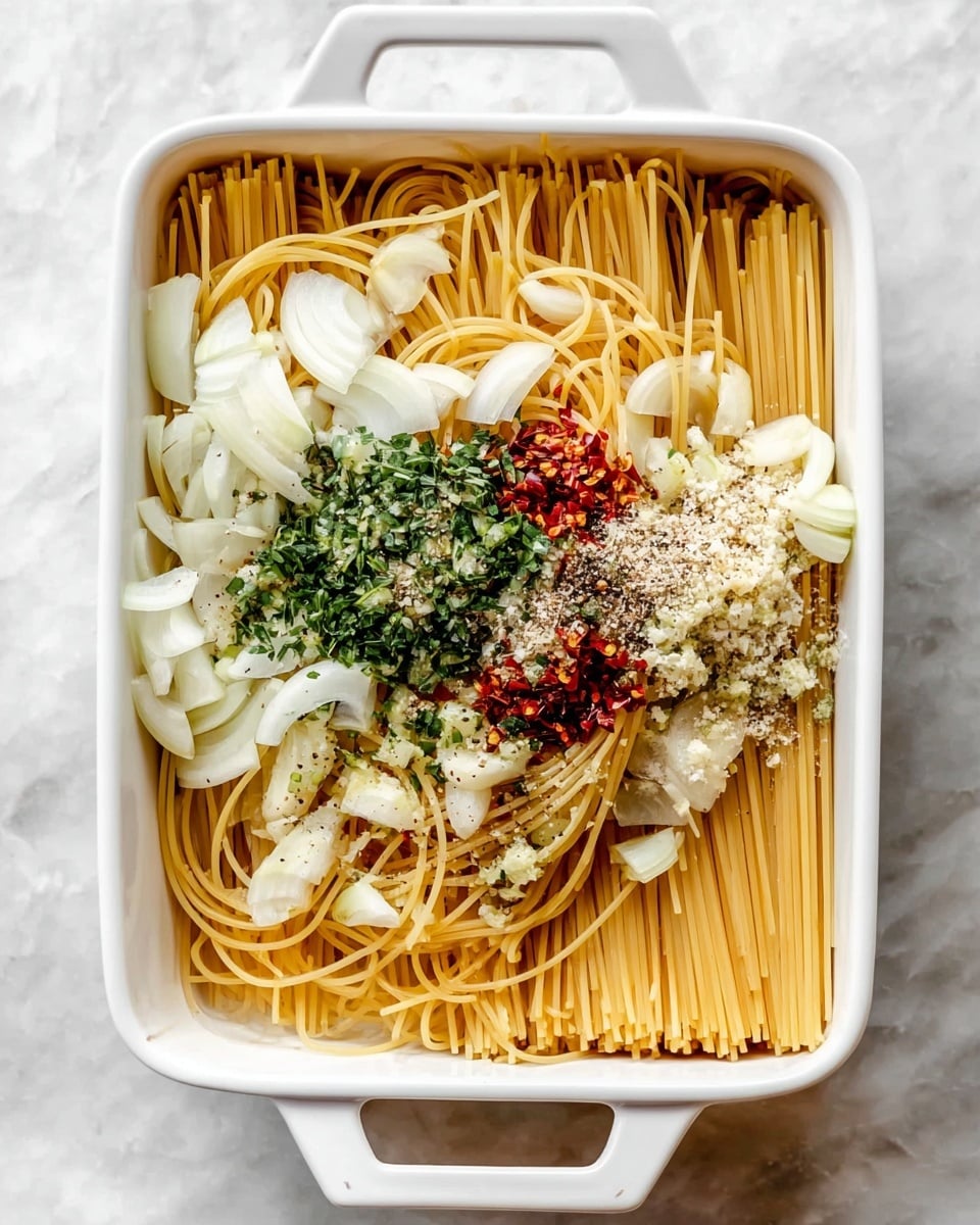 A white rectangular baking dish filled with uncooked spaghetti noodles arranged in a neat, parallel layer, topped with sliced white onion rings and small bits of herbs and seasoning. A light yellow sauce is being poured over the noodles from a white jug on the left side, with the sauce slowly covering the pasta. The texture shows the dry spaghetti sticks in straight lines, thin onion rings scattered on top, and the smooth sauce flowing gently. The background is a white marbled surface. Photo taken with an iphone --ar 4:5 --v 7