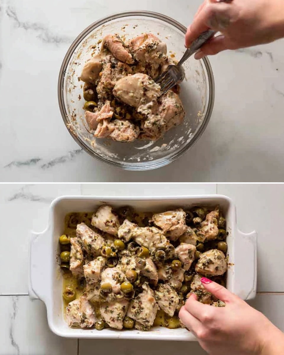 The image shows a white plate with a base layer of fluffy white rice spread evenly in the center. On top of the rice, there are two pieces of cooked chicken thighs, golden-brown with some charred edges, covered with a sauce that contains green olives and capers. The olives are sliced and whole, scattered on the chicken, adding green and yellowish hues mixed with dark herbs and bits of parsley. To the left side of the plate, there is a piece of crusty bread with a light golden crust and soft inside. A silver fork rests on the right edge of the plate, which is placed on a white marbled surface with a small bunch of fresh parsley in the background. The overall look is warm and inviting. photo taken with an iphone --ar 4:5 --v 7