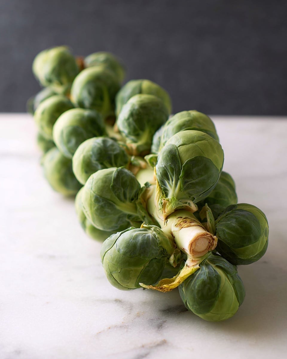 A white bowl filled with a tall pile of roasted Brussels sprouts, showing browned and crispy textures. The Brussels sprouts have different shades of green and light brown caramelized edges. Small pieces of red chili peppers add bright red spots throughout the dish. Chopped green onions are sprinkled on top, giving a fresh, vibrant green contrast. White sesame seeds are scattered over the dish, adding small white dots. The bowl is set on a white marbled surface with a striped cloth underneath. Photo taken with an iphone --ar 4:5 --v 7