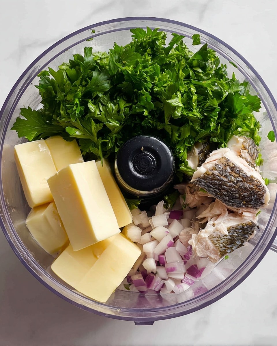 Inside a clear round blender bowl, there are four different layers of ingredients placed close but not mixed. On the right side, there are light pink fish fillets with dark edges. Next to the fish, there are small pieces of purple and white chopped onion. On the bottom left side, there are three thick pale yellow blocks of butter. On the top left, a large bunch of bright green leafy herbs fills the space. The background is a white marbled surface. photo taken with an iphone --ar 4:5 --v 7