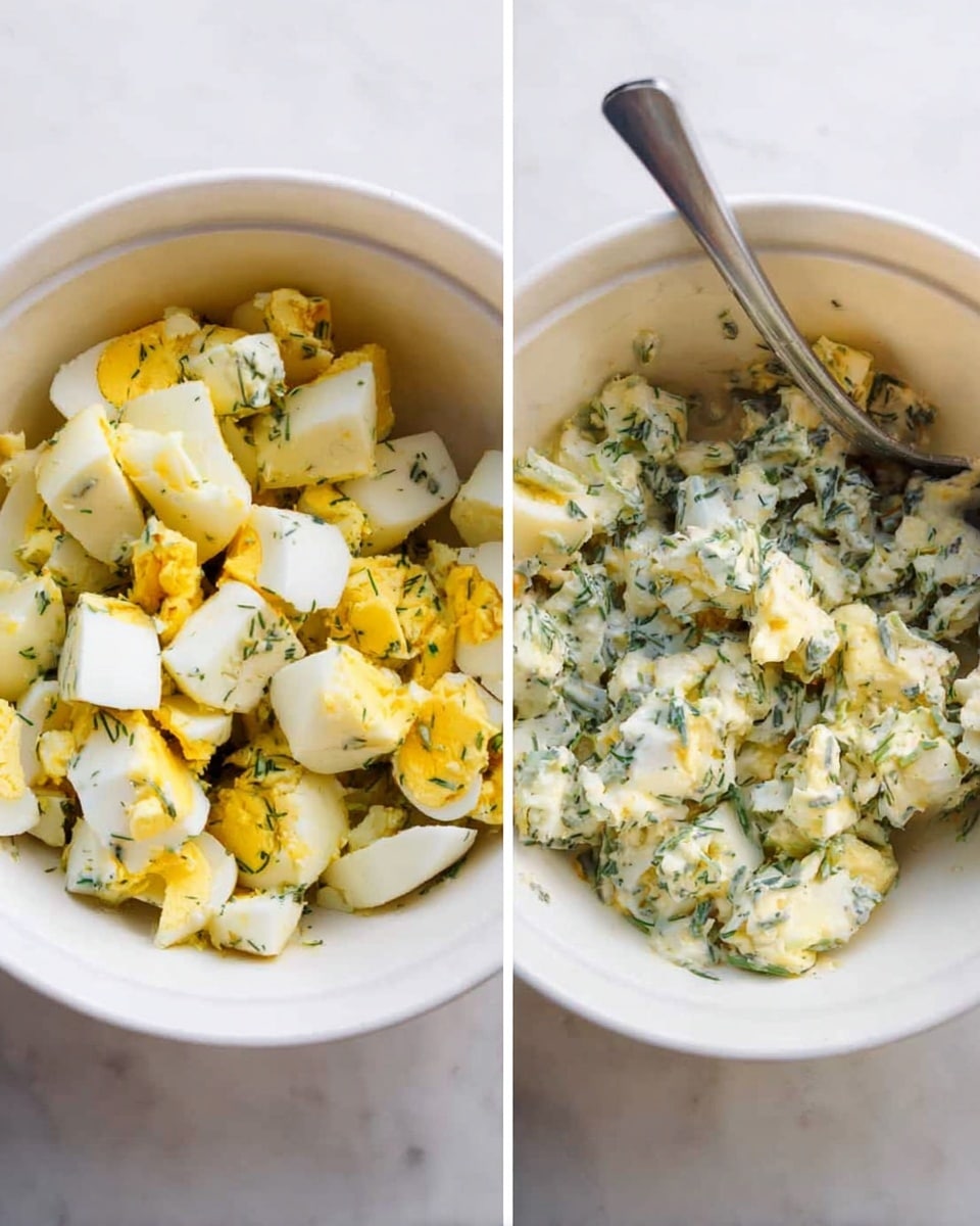 The image shows two white bowls side by side on a white marbled surface. The bowl on the left is filled with chunks of hard-boiled eggs, which are a mix of white and bright yellow yolks, along with some green herbs mixed in. There is a metal fork sticking into the bowl from the right side. The bowl on the right holds a mixture of the same chopped eggs and herbs but now blended together with a creamy dressing, which makes the texture look softer and more combined. Both bowls reflect the colors and textures clearly, with the creamy dressing light yellow with green herb specks. Photo taken with an iphone --ar 4:5 --v 7