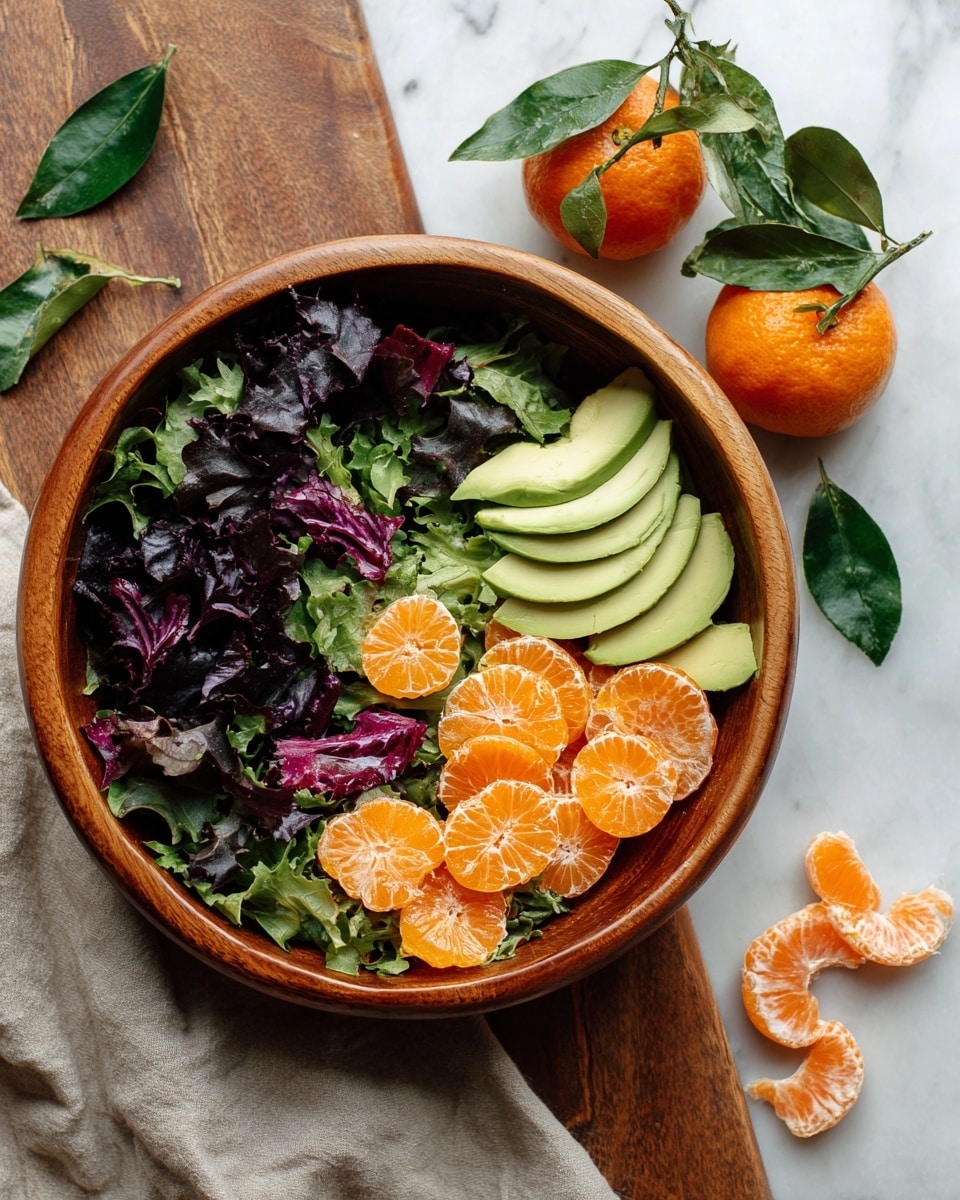The dish shows a white round plate filled with a fresh salad made of dark green spinach leaves, curly green lettuce, and some purple leafy greens as the base layer. On top are small orange segments scattered around, along with slices of light green avocado. Two golden brown sesame-crusted chicken strips with a crunchy texture sit across the middle, lightly drizzled with a creamy yellow dressing. The plate rests on a white marbled surface. Photo taken with an iphone --ar 4:5 --v 7