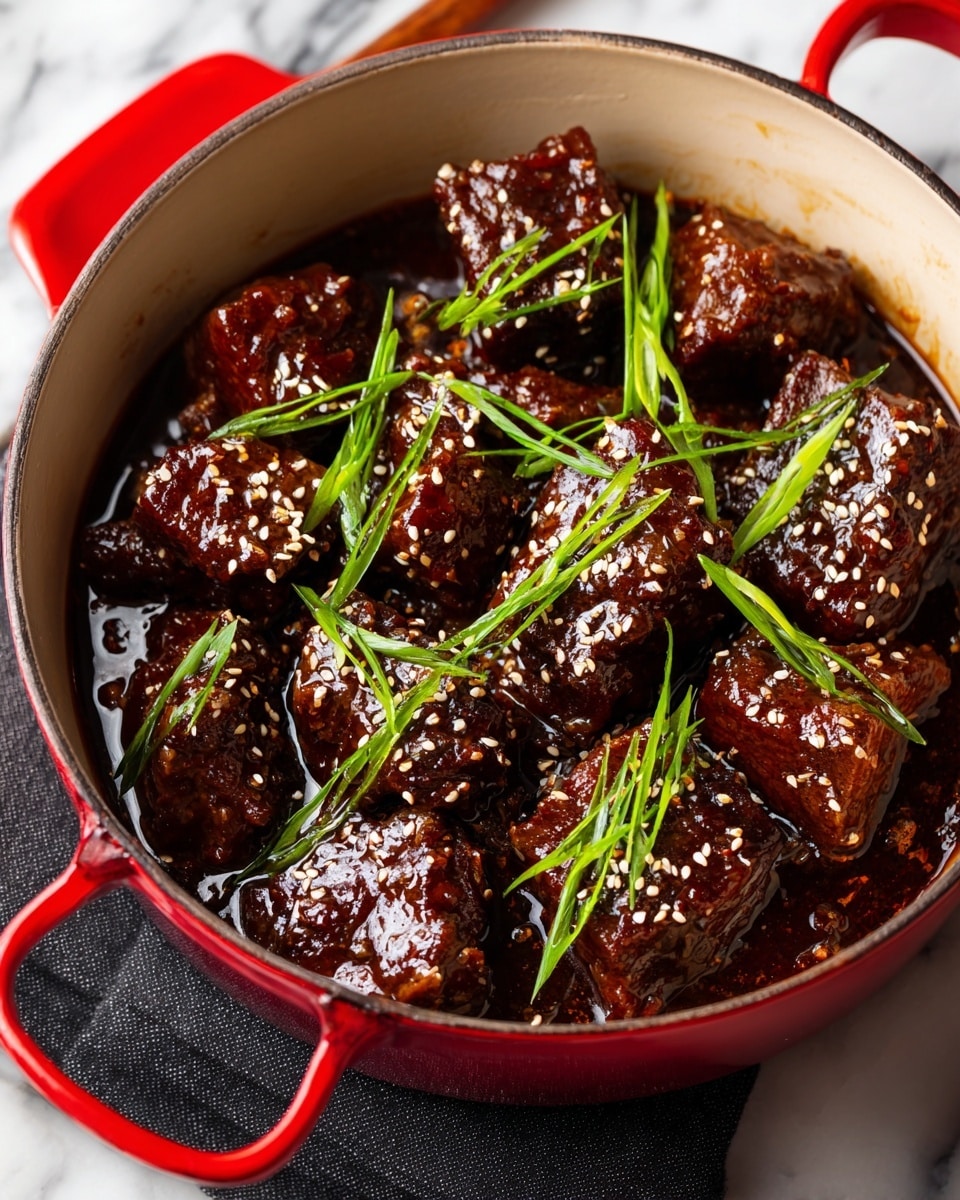 A red pot filled with several large, dark brown chunks of stewed meat covered in a thick, glossy sauce. The meat pieces are sprinkled with white sesame seeds and garnished with thin, long slices of bright green onion scattered evenly on top. The sauce has a shiny, rich texture with some caramelized bits visible in between the meat, creating a deep, appetizing appearance. The pot sits on a black cloth over a white marbled surface. Photo taken with an iphone --ar 4:5 --v 7