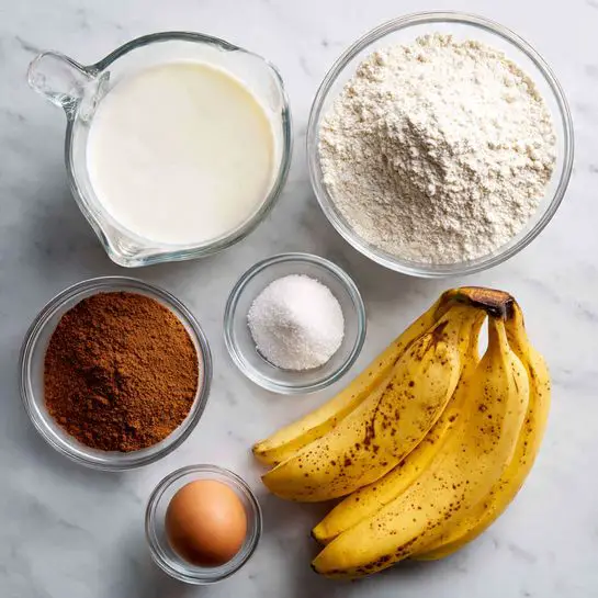 The image shows six ingredients arranged on a white marbled surface: a glass measuring cup with white milk on the top left, a clear bowl filled with white flour in the center top, a small clear bowl with white powdered sugar, brown cinnamon powder, and white salt on the top right, a small clear bowl holding a brown egg at the bottom left, and two yellow bananas with some brown spots on their peel positioned at the bottom right, close to each other and slightly angled. Photo taken with an iphone --ar 4:5 --v 7