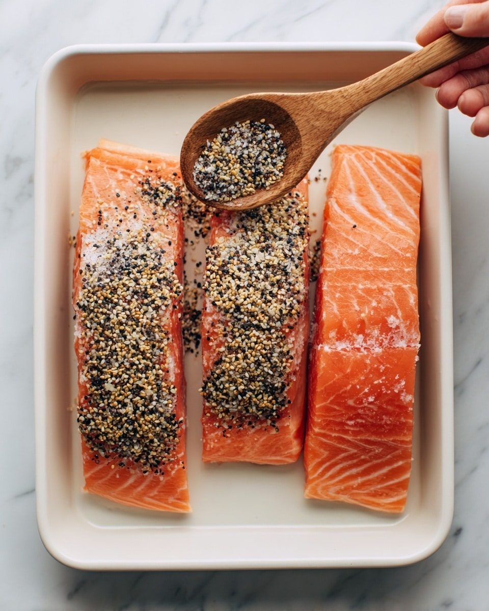 The image shows fresh ingredients spread out on a white marbled surface. There are four bright orange salmon fillets placed side by side on a white plate at the center right. Above them, a dark green cucumber and a purple onion sit side by side with a whole dark green avocado nearby. Surrounding the salmon are small white bowls holding different items: olive oil, cream, yogurt, mayonnaise, capers, and a small amount of brown paste. To the left, a larger white bowl contains green and red leafy lettuce and spinach. Below that, a white bowl holds red and yellow cherry tomatoes. At the bottom, fresh green dill lays on a white oval plate, and next to it, a white bowl contains red radishes with green tops. Two small dishes have black pepper with salt and a mix of seeds with a small wooden spoon. A single clove of garlic is placed near the right edge. photo taken with an iphone --ar 4:5 --v 7