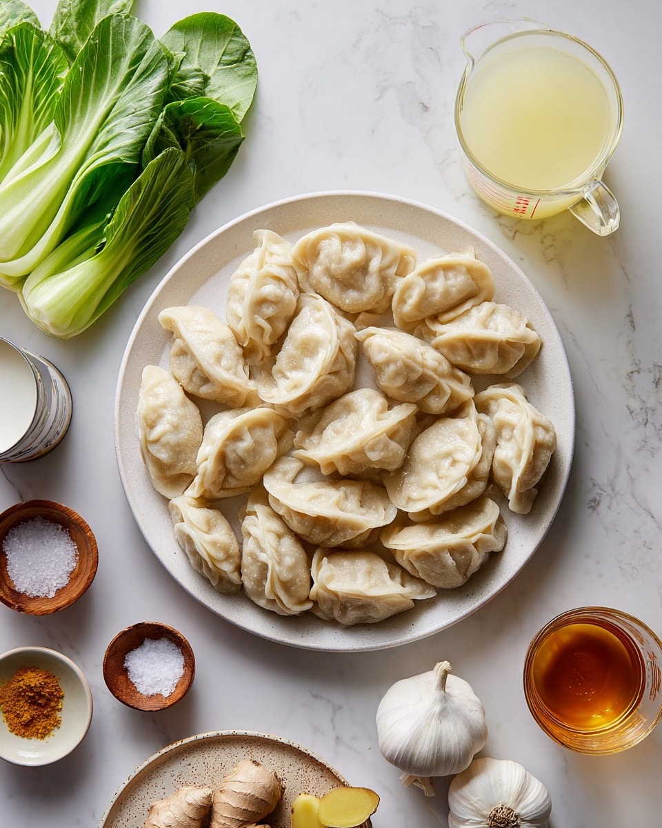 A white bowl filled with a creamy, light orange soup that has visible small red chili oil drops on the surface. Inside the soup are about ten pale dumplings with crimped edges floating around. There are also bright green leafy herbs and a few green onion slices scattered on top. On one side of the bowl, two lime slices lean against fresh green bok choy leaves. A silver spoon is resting in the bowl, partially under one dumpling. The bowl is placed on a white marbled surface with a small glass bowl of dark red chili oil nearby. Photo taken with an iphone --ar 4:5 --v 7