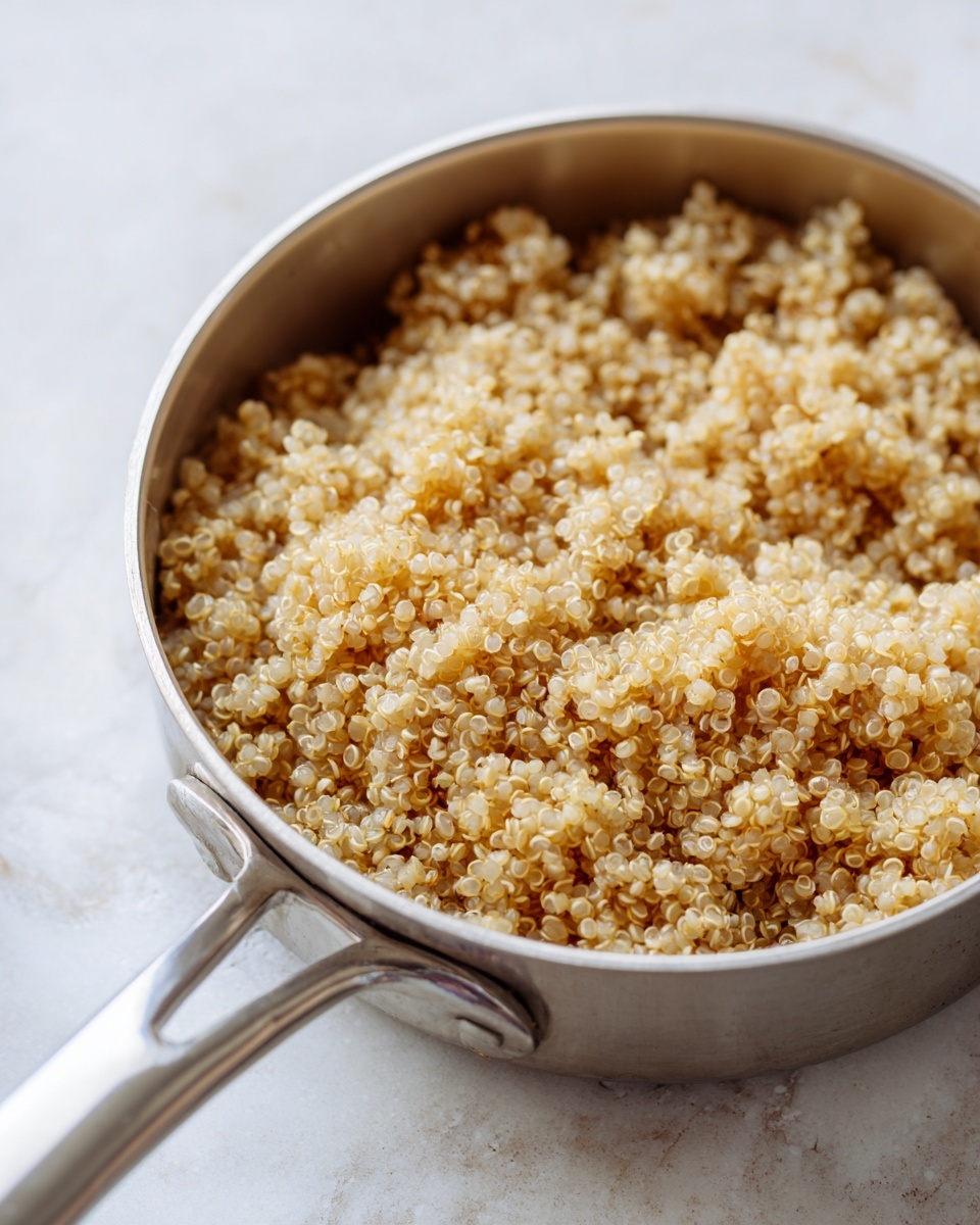 A white bowl filled with a colorful quinoa salad on the left side, showing small grains mixed with bright yellow, red, green, and purple chopped vegetables and herbs. On the right side of the bowl, there are several triangular yellow corn tortilla chips stacked slightly overlapping each other. A wedge of lime and a small green cilantro leaf sit on top of the chips near the salad. A metal fork rests on the left edge of the bowl, partially in the salad. The background is a white marbled texture with some cilantro leaves placed casually near the bowl. Photo taken with an iphone --ar 4:5 --v 7