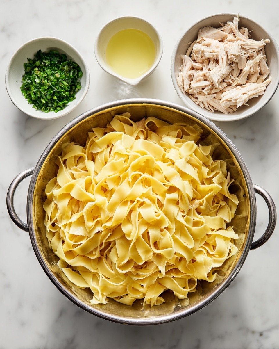 A metal colander sits in the middle filled with many wide, flat, yellow pasta noodles that have a soft, slightly glossy texture. Around the colander on a white marbled surface are three small white bowls: the top left bowl holds bright green chopped herbs, the bottom left bowl contains shredded light beige cooked chicken, and the top right bowl has a small amount of pale yellow liquid. The scene is bright and clean, showing the pasta and ingredients clearly. photo taken with an iphone --ar 4:5 --v 7