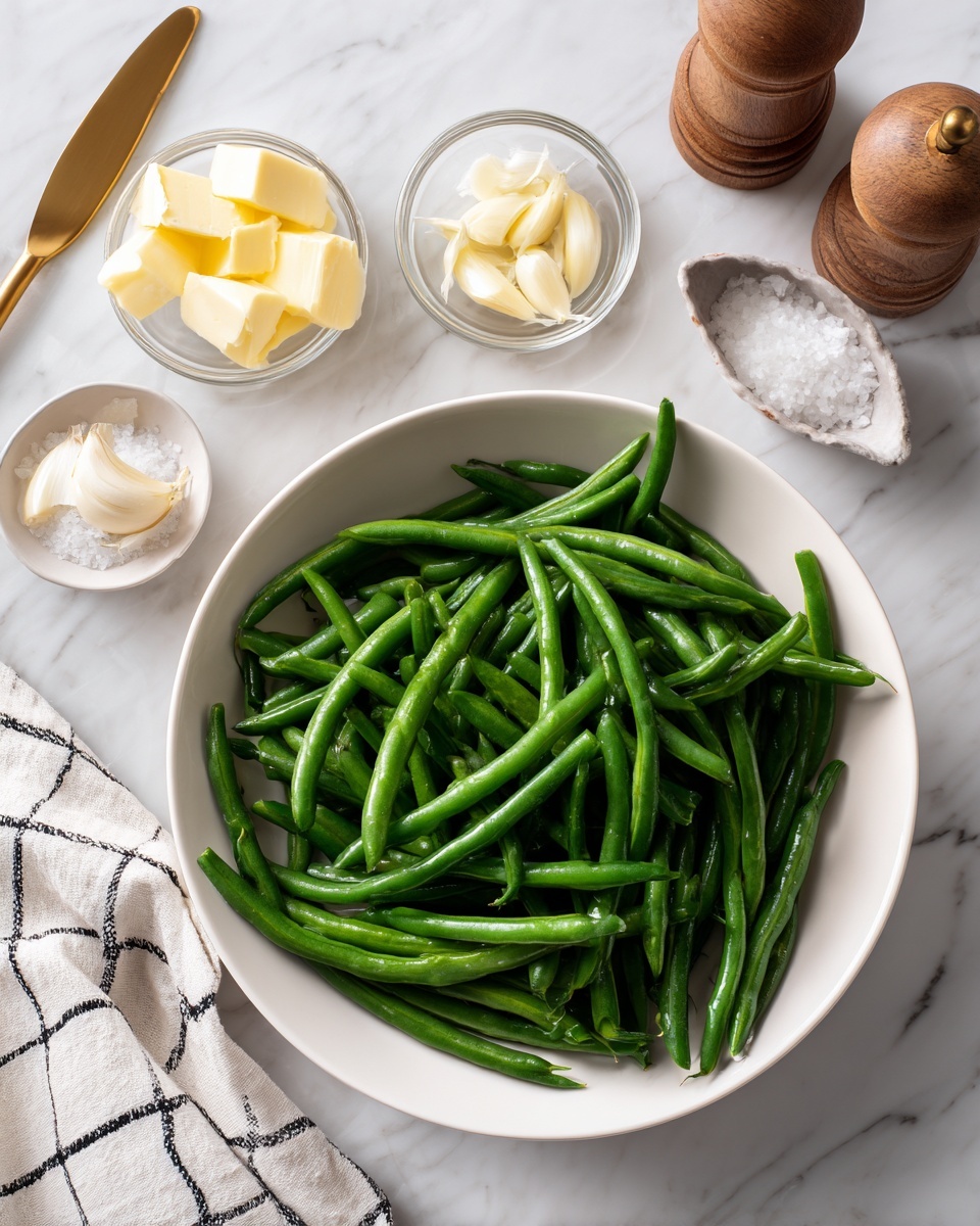 A white bowl filled with fresh green beans sits on a white marbled surface, surrounded by small clear glass containers holding light yellow butter pieces and thinly sliced garlic. Nearby is a white round container with white salt and a small gold spoon resting inside, alongside a wooden pepper grinder. A white cloth with a black grid pattern is casually placed to the left side, creating a soft contrast with the smooth marbled texture. photo taken with an iphone --ar 4:5 --v 7