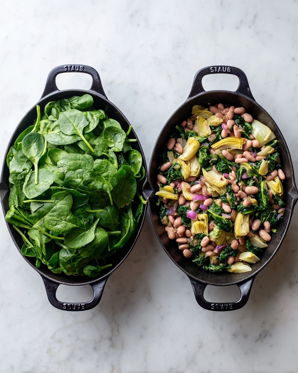 The image shows two black cast iron pans side by side on a white marbled surface. In the left pan, there is a large pile of fresh, bright green spinach leaves stacked loosely, covering the pan fully. In the right pan, the spinach has cooked down and mixed with light pink beans, pale yellow artichoke pieces, and small chunks of light brown onion, giving a colorful mix of greens, pinks, and yellows spread evenly throughout the pan. The pans have two handles each, with the word
