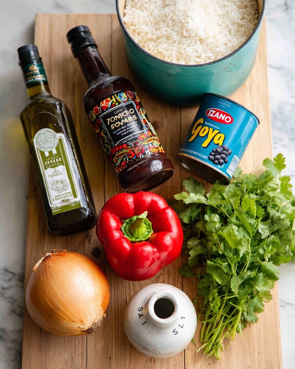 A variety of ingredients are neatly arranged on a light wooden surface. On the left, there is a clear bottle of olive oil with green and white labeling, next to a dark brown bottle of Izano salsa sauce with colorful red and green details. Beside these, a blue can of Goya black beans stands upright, its bright yellow and white text clearly visible. In front of the bottles and can, a fresh red bell pepper with a green stem is centered, flanked by a large golden brown onion on the left and a round white garlic bulb below it. To the right, a white ceramic jar labeled