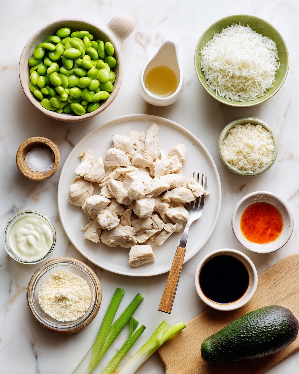 The image shows a top view of various food ingredients arranged on a white marbled surface. In the center, there is a white plate filled with torn light beige cooked chicken pieces, with a small wooden fork resting beside them. To the top left, there is a white bowl holding bright green edamame beans, and above that, a small white sauce dish with a golden liquid inside. To the top right, a green bowl is filled with white cooked rice. Below the chicken plate, there is a small white bowl filled with panko breadcrumbs. Near the bottom left, a glass bowl contains a creamy white sauce, and above it, three fresh green onions with white roots laying horizontally. At the bottom right on a small wooden board, there is a whole dark green cucumber. Scattered around are an avocado with dark brown skin near the center, a small white bowl of dark soy sauce below the edamame, and a small white bowl with an orange-red sauce on the right side. Photo taken with an iphone --ar 4:5 --v 7