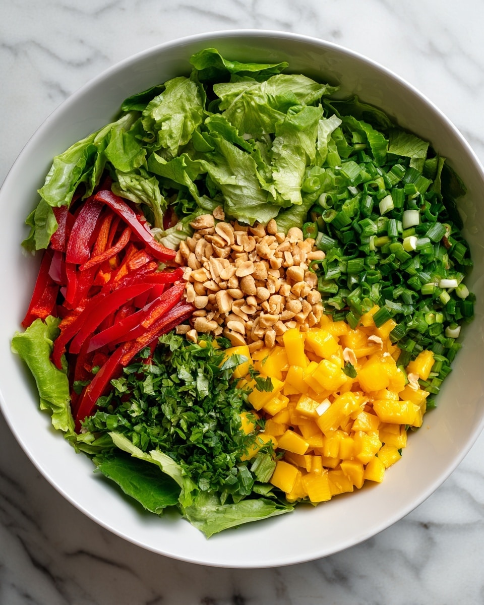 A white round bowl holds a colorful layered salad on a white marbled surface. The bottom layer is fresh leafy green lettuce at the front, followed by thin red bell pepper strips on the left side. Above them is a thick layer of bright green chopped scallions. To the right side, there is a chunky layer of small yellow mango cubes mixed with chopped green herbs. In the center of the bowl, a layer of coarsely chopped peanuts adds a light tan texture. The ingredients are arranged in neat sections, creating a vibrant and fresh look. Photo taken with an iphone --ar 4:5 --v 7