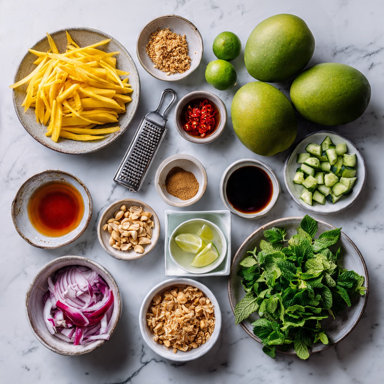A white bowl sits on a white marbled surface, filled with a colorful salad. The bottom layer is thin yellow strips of mango mixed with thin slices of red onion and red chili peppers. There are also thin green cucumber strips spread evenly. Fresh green mint leaves and cilantro are scattered across the top. In the center, there is a small pile of golden brown fried shallots and crushed peanuts sprinkled over the salad. Two lime wedges rest on the right side inside the bowl. Around the bowl, there are three smaller white bowls with extra fried shallots, crushed peanuts, and lime wedges with cilantro. A white napkin with wooden chopsticks wrapped in white cloth is placed at the lower right. The photo taken with an iphone --ar 4:5 --v 7