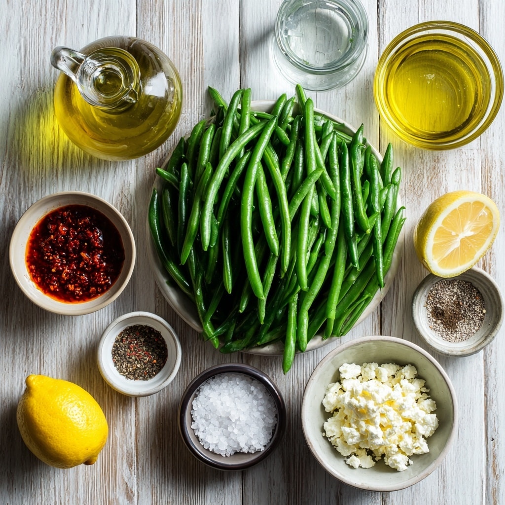 The image shows a black frying pan filled with bright green beans that are cooked and shiny with some small red seasoning specks on them. The green beans are mostly whole and layered unevenly across the pan, with some light sauce or oil pooling slightly on one side. The pan is placed on a stove with a blurred white marbled surface around it. The beans have a smooth texture and a fresh look. photo taken with an iphone --ar 4:5 --v 7