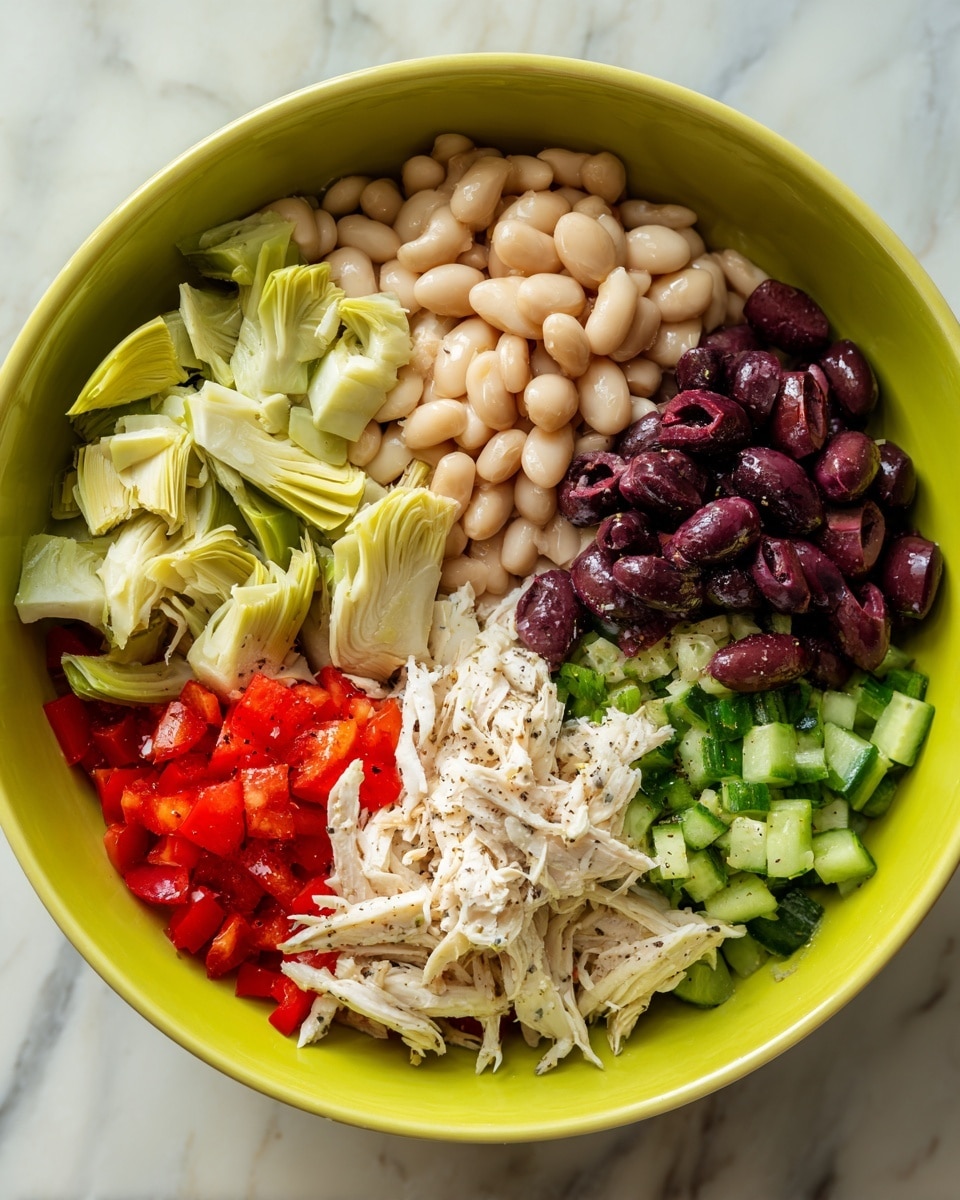A bright lime green bowl sits on a white marbled surface, filled with six distinct layers of ingredients arranged side by side without mixing. Starting from the top left, there are light green artichoke pieces with a soft texture, next to a pile of beige cannellini beans. Below the beans, shredded white chicken is visible with delicate strands, and above the chicken, there are dark purple chopped olives with a shiny surface, sprinkled with black pepper. To the bottom left, a mix of chopped red bell peppers and green cucumbers with a crisp texture fills the space. The ingredients form a colorful and fresh combination with clear, separate sections. Photo taken with an iphone --ar 4:5 --v 7