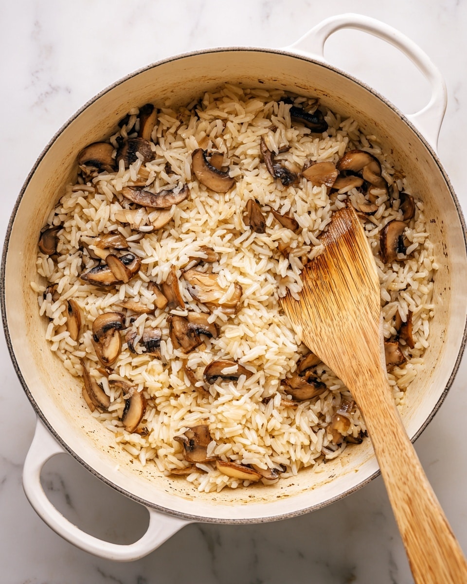 A white pot filled with a mixture of rice and sliced mushrooms cooking together. The rice grains are pale beige and scattered all around, some stuck slightly to the pot's bottom, showing light browning. The mushrooms are sliced thin, light brown with darker edges, mixed evenly throughout the rice. A wooden spatula is resting inside the pot on the right side, partially covered by the rice and mushrooms. The pot is placed on a white marbled surface, visible beneath the pot's handles and around its base. Photo taken with an iphone --ar 4:5 --v 7