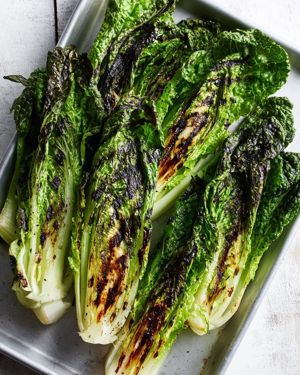 This image shows four halves of grilled romaine lettuce placed on a white metal tray with a white marbled background. Each lettuce half has a base of white and light green stem, with several layers of larger green leaves overlapping above. The lettuce leaves have charred grill marks, showing a mix of deep green and brown colors on their textured, ruffled surfaces. The layers are thick and leafy, with the outer leaves looking slightly wilted from cooking. The image is bright with natural lighting, highlighting the freshness and texture of the grilled lettuce. Photo taken with an iphone --ar 4:5 --v 7