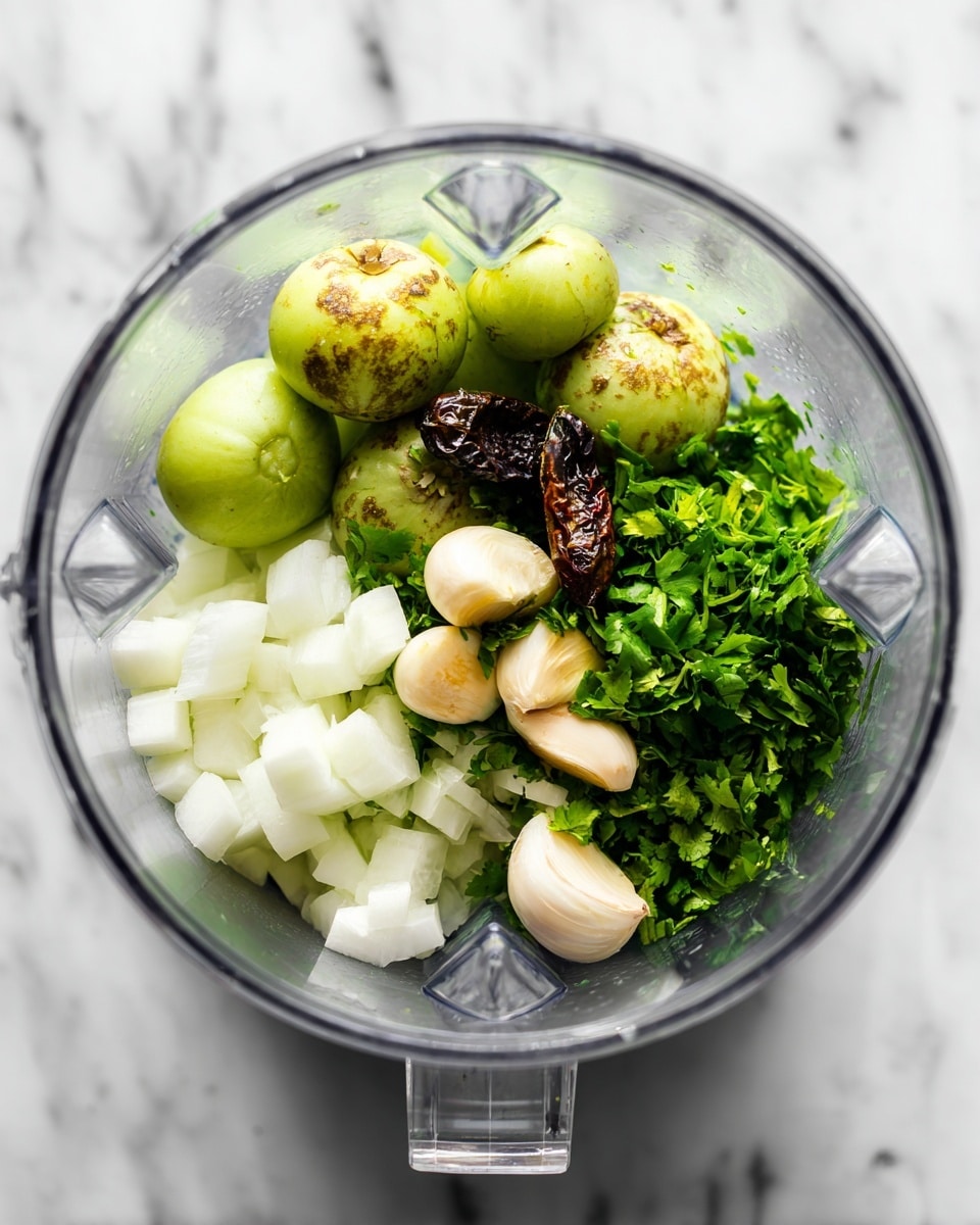 Inside a clear blender jar on a white marbled surface, there are several ingredients layered and grouped. At the bottom right, there is a pile of bright green chopped cilantro leaves. Next to that on the left side, there is a heap of small white onion cubes. On top and to the center-right, there are four round, light green tomatillos with some brown charred spots. Around the tomatillos are a few dark green and brown charred peppers and four peeled garlic cloves with some brown marks, positioned near the center. The clear blender jar has sharp edges and is viewed from above. photo taken with an iphone --ar 4:5 --v 7