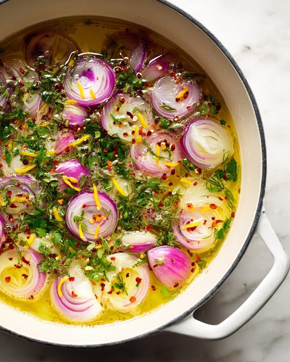 This image shows a close-up of a white pot filled with bubbling light golden liquid. Inside the liquid, thinly sliced rounds of purple shallots float, mixed with bright green fresh herbs scattered on top. There are also thin strips of yellow lemon zest spread throughout. Small red chili flakes add a touch of color contrast. The pot is placed on a white marbled surface. The scene captures a warm and fresh cooking moment. photo taken with an iphone --ar 4:5 --v 7